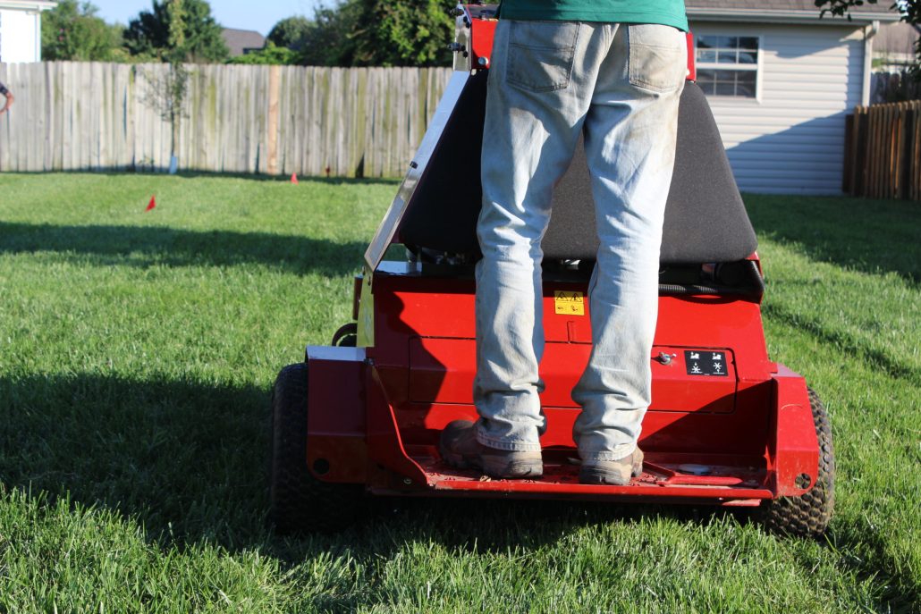 A PURE Lawn Management technician performing core aeration on a lawn with the core aerator machine.
